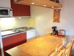 A compact kitchen with a microwave, stove, sink, and a coffee maker on the counter.