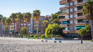 A beachfront residential area with multi-story buildings, palm trees, and a sandy beach. - Seaside apartment with air conditioning and private parking (Torredembarra)