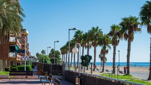 A coastal promenade with benches, palm trees, and a view of the beach. - Seaside apartment with air conditioning and private parking (Torredembarra)