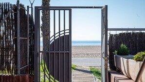 A wooden pathway leading to a beach, with a metal gate and a fence on one side. - Seaside apartment with air conditioning and private parking (Torredembarra)