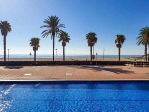 Una piscina con vista a la playa y palmeras.