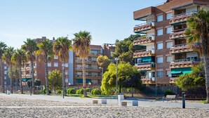 A beachfront residential area with multi-story buildings, palm trees, and a sandy beach. - Sea-front apartment with pool and private parking in Torredembarra (Torredembarra)