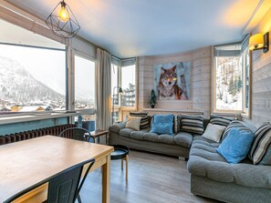 Ein gemütliches Wohnzimmer mit Holzboden, einem Holzesstisch, einer Couch mit gestreiften Kissen und einem Bild von einem Wolf an der Wand.