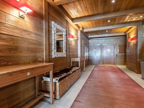 A wooden hallway with a bench, a mirror, and a red carpet.