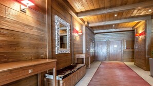 A wooden hallway with a bench, a mirror, and a red carpet.