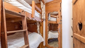 Una cabaña de madera con literas, una escalera y un espejo.