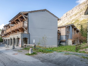 Een klassiek chalet met stenen muren en houten balkons, gelegen tegen een bergachtige achtergrond.