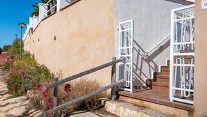 A building with a beige exterior, white railings, and a staircase leading to a balcony. - Seafront Apartment with Terrace and Parking (Altafulla)