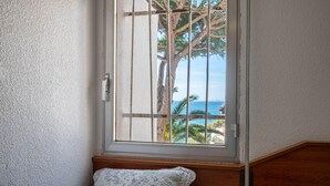 A bedroom with a window overlooking a tree and a view of the sea. - Seafront Apartment with Terrace and Parking (Altafulla)