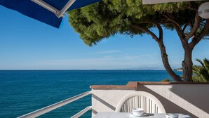 A balcony with a table set for two, overlooking a clear blue sea and a distant coastline. - Seafront Apartment with Terrace and Parking (Altafulla)