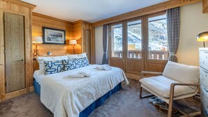 Un dormitorio acogedor con una cama de madera, una silla y ventanas amplias con vistas al exterior.