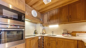 Una cocina con armarios de madera, electrodomésticos de acero inoxidable, un reloj y un lavamanos.