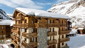 Una cabaña de madera de varios pisos con balcones, ubicada en una zona montañosa nevada.