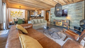 A spacious living area with a leather sofa, a dining table, and a kitchen in the background. - Luxury apartment with pool, WiFi, and parking in Val-d'Isère (Val-d'Isère)