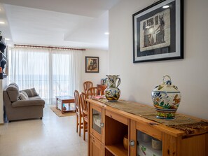 Uma sala de estar com sofá, mesa de jantar, cadeiras, um armário e um vaso grande.