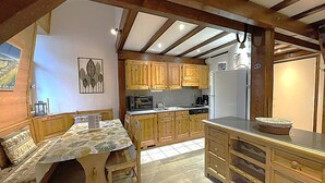 Una cocina con armarios de madera, una mesa de comedor con sillas y un refrigerador.