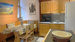 Una cocina acogedora con armarios de madera, microondas y comedor con mesa y sillas.