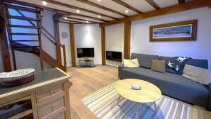 Una sala de estar con un sofá, una mesa de centro, un televisor y una escalera.