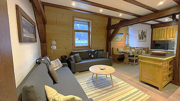 Una sala de estar acogedora con sofá, una mesa de centro y una cocina con armarios de madera y microondas.