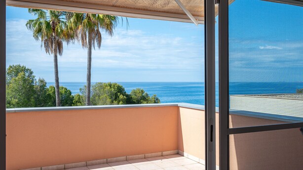 Un balcón con vista al mar y palmeras.