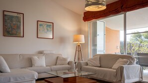 Una sala de estar moderna con una mesa de centro de vidrio, dos sofás blancos y una lámpara de pie.
