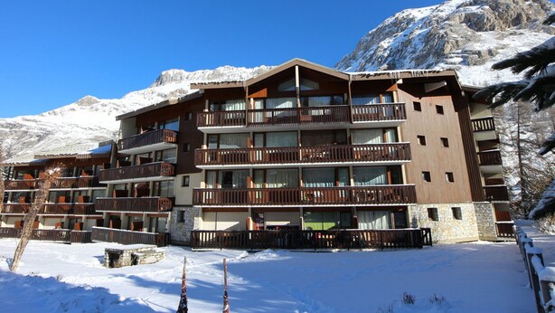 Ett hotell med flera våningar och balkonger, beläget med en snötäckt bergskedja som bakgrund.
