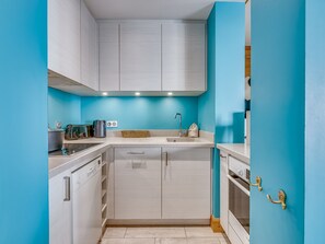A modern kitchen with white cabinets, a sink, and a stove. - Elegant and Bright High-End Apartment with South-Facing Terrace in Central Val-d'Isère near the Slopes (Val-d'Isère)