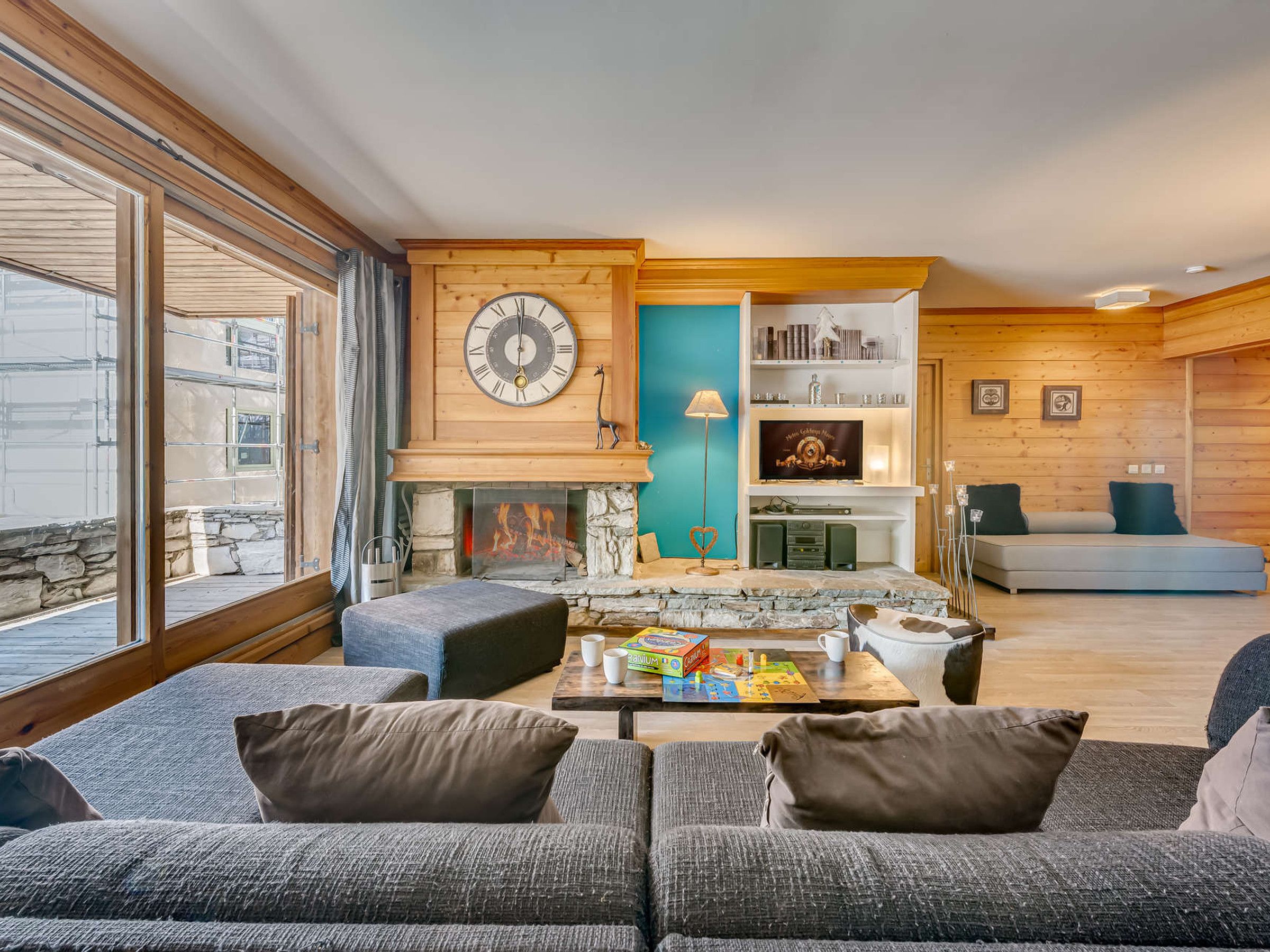 A modern living room with a fireplace, a large clock, and a cozy seating area.