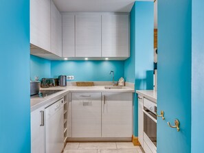 A modern kitchen with white cabinets, a sink, and a stove. - Elegant and Bright High-End Apartment with South-Facing Terrace in Central Val-d'Isère near the Slopes (Val-d'Isère)