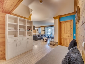 A spacious living area with a sofa set, a wooden cabinet, and a dog.