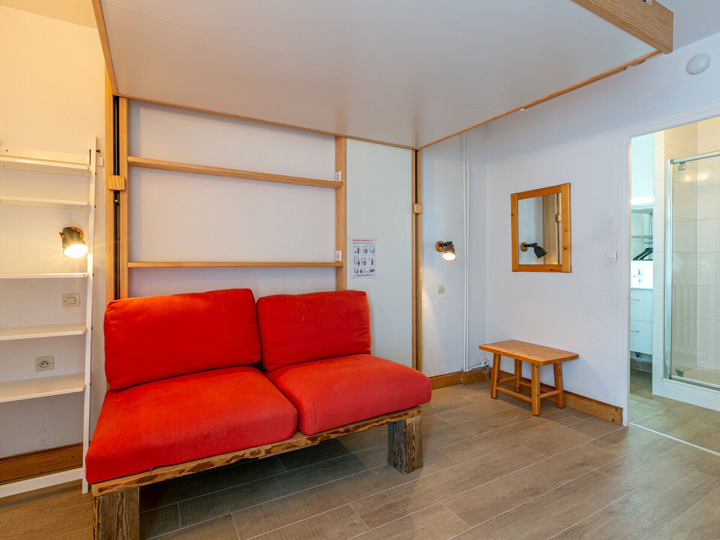 A room with a wooden bench, a small wooden table, and a mirror on the wall.