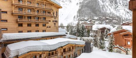 A wooden chalet-style hotel with multiple balconies and a ski slope in the background.