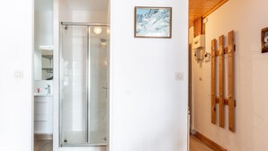 Ein modernes Badezimmer mit Duschkabine aus Glas, einer Holzwand mit montierten Skiern und einem gerahmten Bild von einem verschneiten Berg.