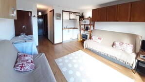A compact living space with a kitchenette, a sofa, a dining table, and a bed.