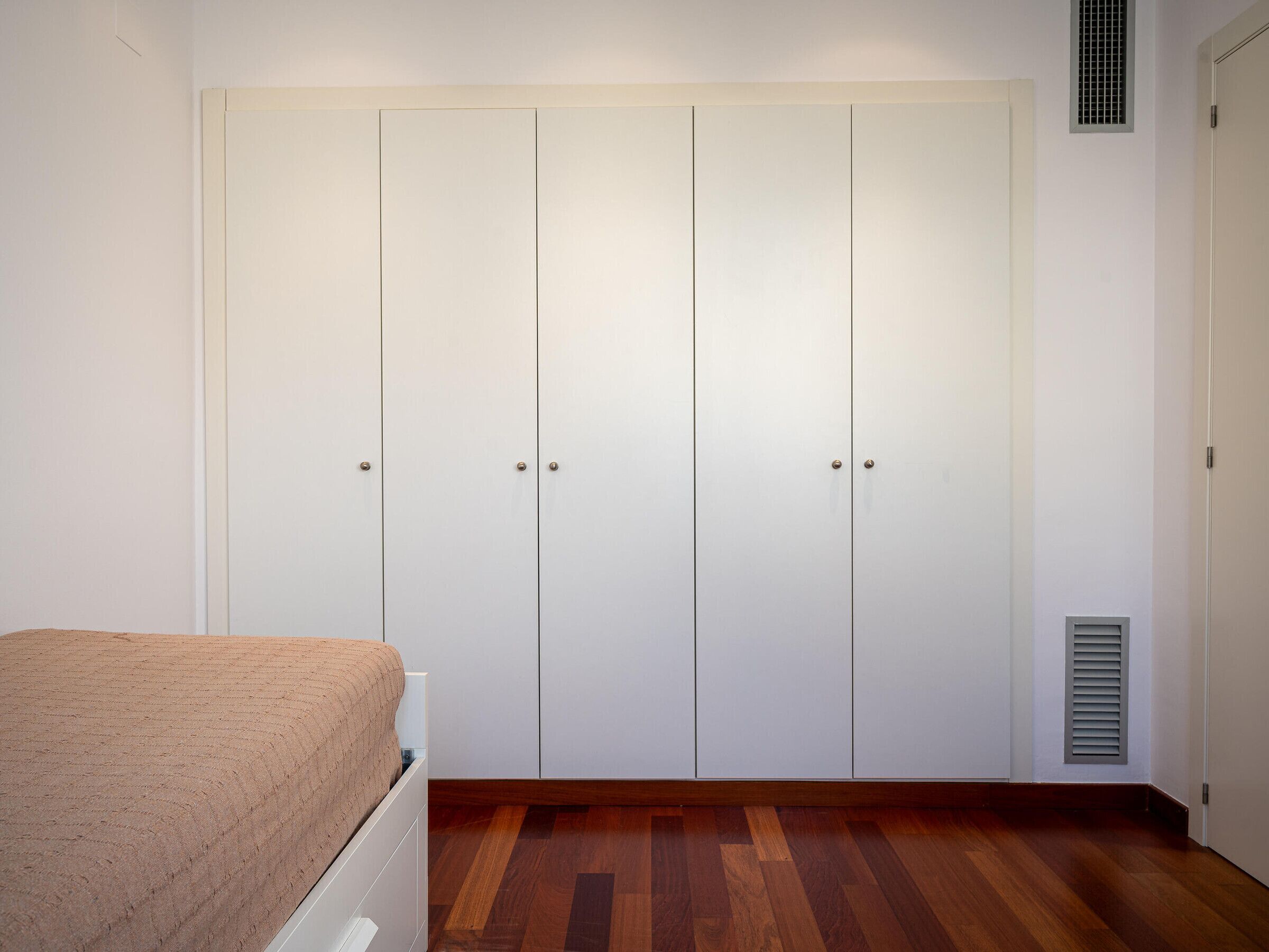 Une chambre à coucher avec un lit, une armoire et une bouche d’aération.