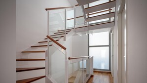 A modern staircase with glass railings and wooden steps.