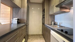 Une cuisine étroite avec des meubles de rangement en bois, un four encastré et un lave-vaisselle.