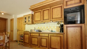 Eine Küche mit Holzschränken, einem schwarzen Backofen und einer gefliesten Spritzschutzwand.