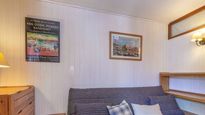 A room with a bed, a wooden nightstand, a framed picture, and a wall-mounted lamp. - **Cozy Ski-In/Ski-Out Apartment Near Children's Village, Sleeps 5** (Val-d'Isère)
