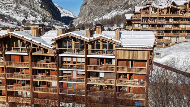 A wooden lodge with multiple balconies and a mountainous backdrop. - Elegant apartment in Val-d'Isère with balcony, parking, wifi (Val-d'Isère)