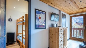 A cozy room with a bunk bed, a wooden dresser, a television, and a framed picture on the wall. - Elegant apartment in Val-d'Isère with balcony, parking, wifi (Val-d'Isère)