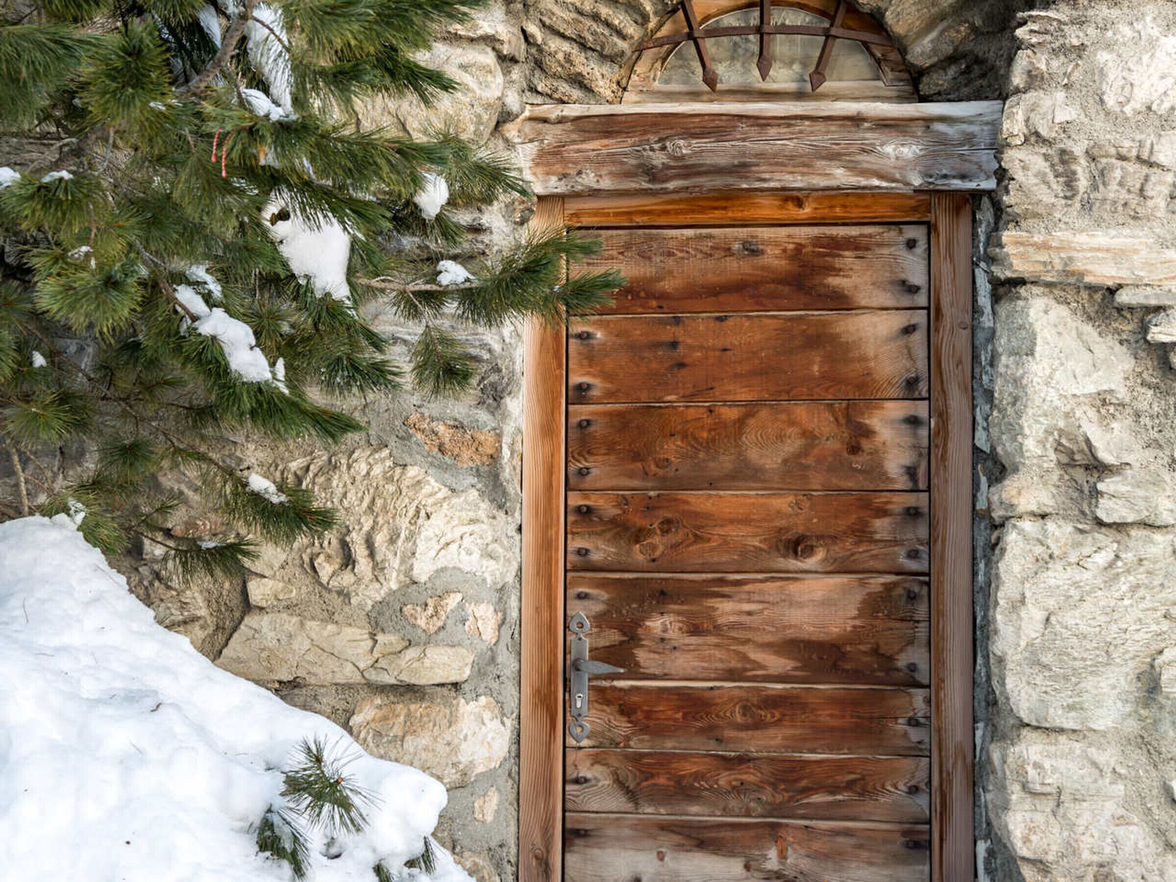 A wooden door with metal hinges and a stone wall.