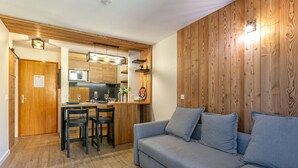 Eine moderne Küche mit Holzausstattung, ein Essbereich mit grauem Sofa und einer Holzwand.