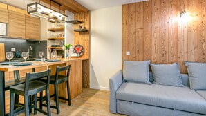Eine moderne Küche mit Holzausstattung, ein Essbereich mit Bar und ein graues Sofa im Wohnraum.