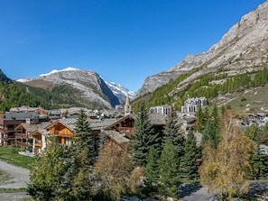 A mountain town with wooden buildings, a church, and snow-capped peaks in the background.