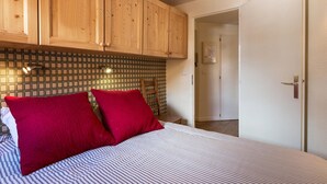 Een slaapkamer met houten kasten, een betegelde spatwand en een bed met gestreept beddengoed.