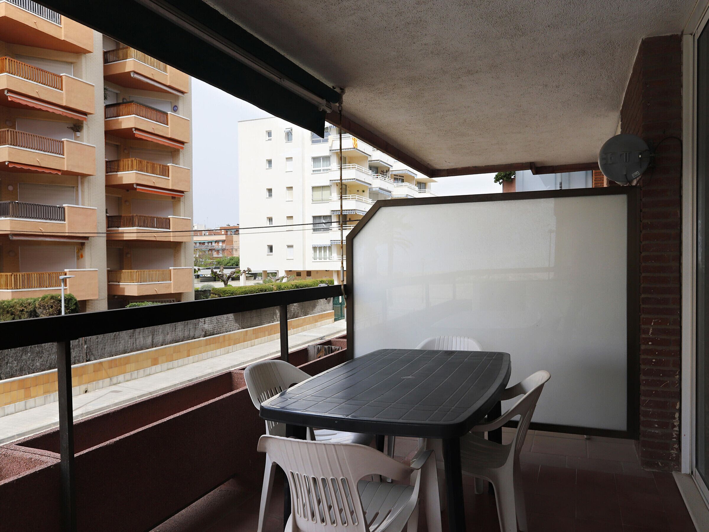A balcony with a table and chairs, overlooking a residential area with multiple apartment buildings.