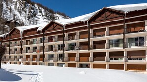 Um hotel com vários andares, varandas e uma montanha nevada ao fundo.