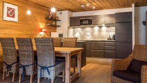 A cozy kitchen with a wooden ceiling, a dining table with wicker chairs, and a microwave. - Luxury apartment in the center, pets allowed, WiFi (Val-d'Isère)