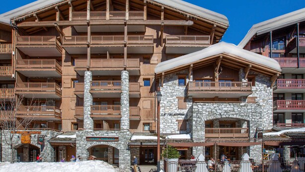 A multi-story hotel with stone and wood construction, balconies, and a ski slope in the background. - Luxury apartment in the center, pets allowed, WiFi (Val-d'Isère)